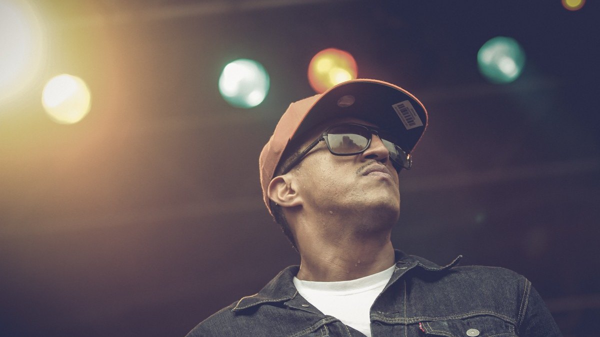 Mano Brown durante show, de boné e óculos escuros, em 2013